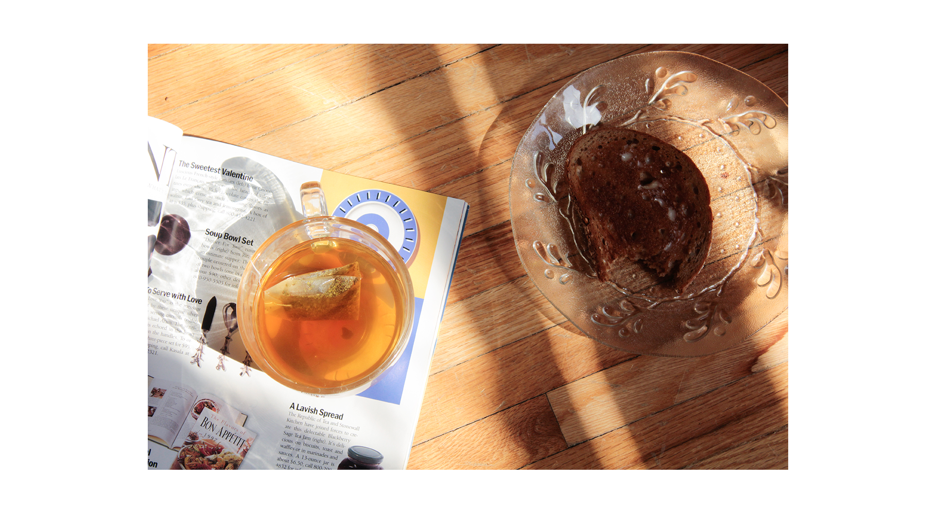 a photo of a tea cup atop a magazine, next to a piece of toast